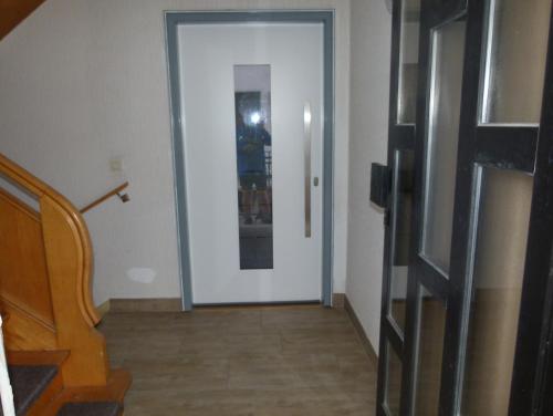 un pasillo con una puerta blanca y una escalera en FeWo Annabell, en Sankt Wendel