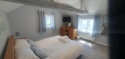 a bedroom with a white bed and two windows at Country Cottage Barn Conversion in Pollington