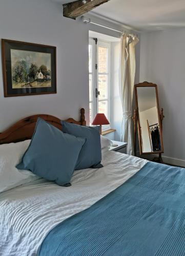 une chambre avec un lit avec des oreillers bleus et un miroir dans l'établissement La petite Maison, à Argenton-Château
