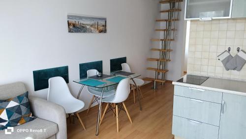 eine Küche mit einem Tisch und Stühlen im Zimmer in der Unterkunft Apartament za wydmą Sosnowa 13 in Mielno