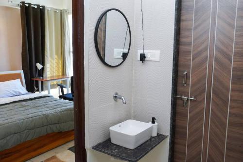 a bathroom with a sink and a mirror next to a bed at A Homely 2 BHK in Main Kharadi - Anandkunj in Pune