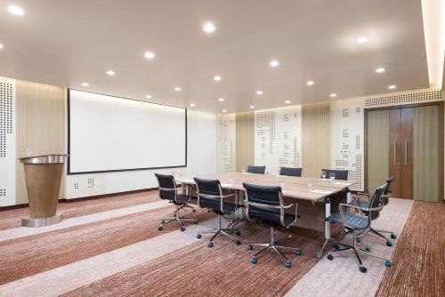 a conference room with a table and chairs and a whiteboard at IntercityHotel Bawshar Muscat in Muscat