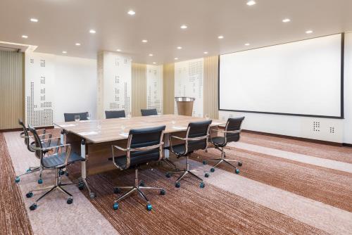 a conference room with a table and chairs and a projection screen at IntercityHotel Bawshar Muscat in Muscat