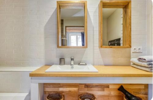 La salle de bains est pourvue d'un lavabo, d'un miroir et d'une baignoire. dans l'établissement Maison de charme Beaumont, proche Deauville, à Beaumont-en-Auge