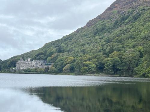 a castle sitting on the side of a mountain next to a lake at Racecourse Lodge Apartment in Clifden