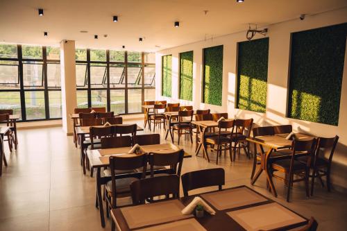a restaurant with tables and chairs and windows at Britto Hotel in Aparecida