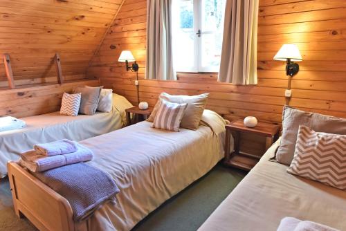 sypialnia z 2 łóżkami w drewnianym domku w obiekcie Cabañas Nonthue by Visionnaire w mieście San Martín de los Andes