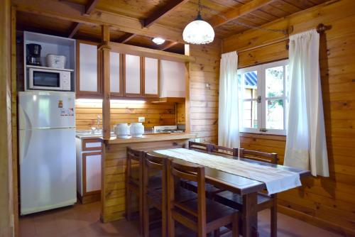 a kitchen with a table and a refrigerator at Cabañas Nonthue by Visionnaire in San Martín de los Andes