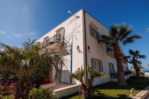 un edificio bianco con una palma di fronte di Marina di Petrolo Hotel & SPA a Castellammare del Golfo