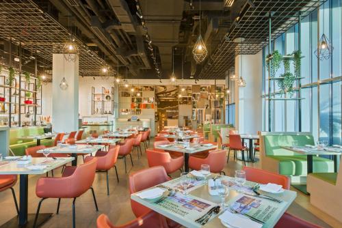 a restaurant with tables and chairs and windows at IntercityHotel Bawshar Muscat in Muscat