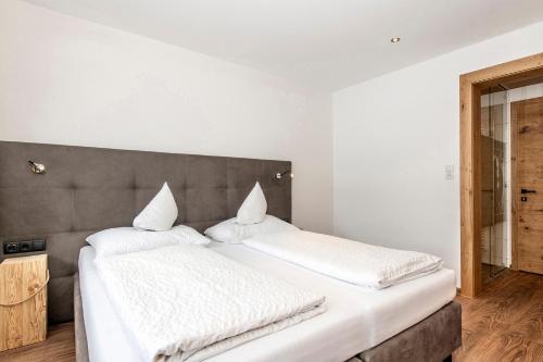a bedroom with two beds with white sheets at Gasthof-Pension Wulfenia in Gargellen