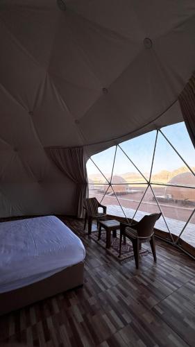 a bedroom with a bed and chairs in a tent at Rum desert magic in Wadi Rum