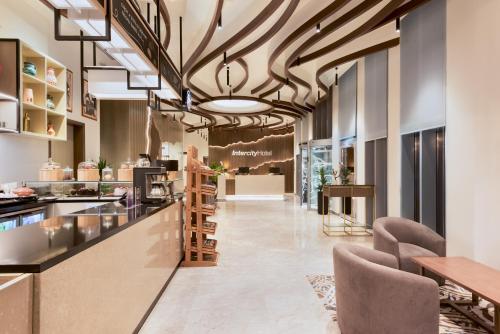 an office lobby with a bar and chairs at IntercityHotel Bawshar Muscat in Muscat