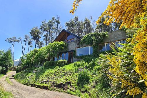 uma casa numa colina ao lado de uma estrada de terra em Puerto Manzano Suites by Visionnaire em Villa La Angostura