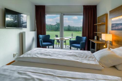 una camera con letto, tavolo e sedie di Strandhotel de Horn a Callantsoog