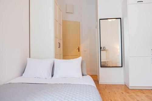 a bedroom with a bed with white sheets and a mirror at Komfortowy Apartament w Centrum in Warsaw