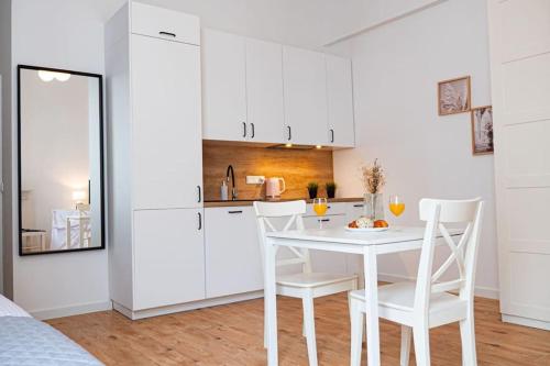 a white kitchen with a white table and chairs at Komfortowy Apartament w Centrum in Warsaw