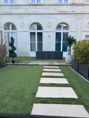 ein Garten mit Gras und Steinen vor einem Gebäude in der Unterkunft Prestigieuse Suite Princeteau in Libourne
