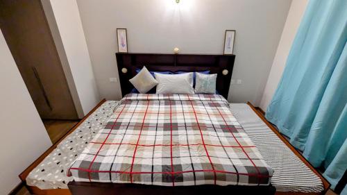 a bed with a plaid quilt on it in a bedroom at New 1BHK at Central Park, Sohna Road, Ayaansh Resort in Gurgaon