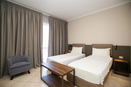 a hotel room with two beds and a table and a chair at Regina Garden Vlore in Vlorë