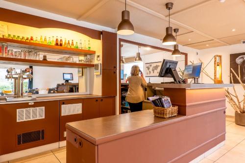 a woman standing at the bar of a restaurant at Kyriad Digne-Les-Bains in Digne-les-Bains