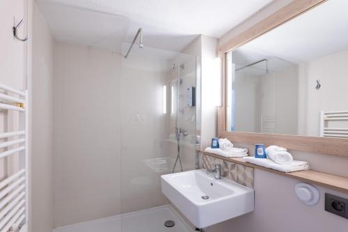 W białej łazience znajduje się umywalka i lustro. w obiekcie Kyriad Digne-Les-Bains w mieście Digne-les-Bains