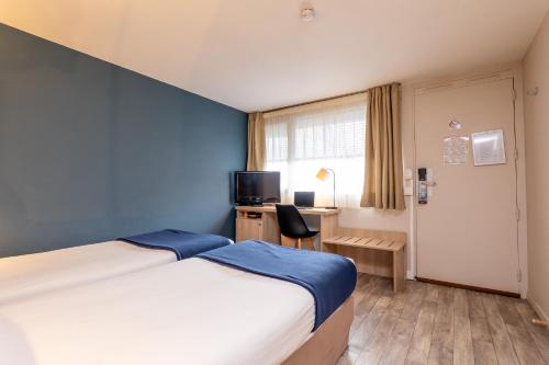 - une chambre avec un lit et un bureau avec une télévision dans l'établissement Kyriad Digne-Les-Bains, à Digne-Les-Bains
