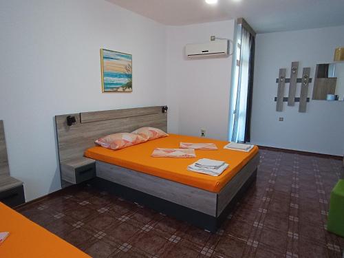 a bedroom with a bed with an orange bedspread at Coral Family Hotel in Chernomorets