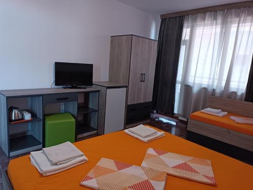 a living room with a table and a tv and a room at Coral Family Hotel in Chernomorets