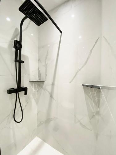 a shower in a white bathroom with a black light at Appartement moderne climatisé Monaco vue Mer in Cap d'Ail