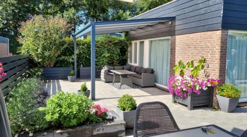 a patio with a table and chairs and flowers at Cozy bungalow (Near beach, tulip fields, etc) in Noordwijkerhout