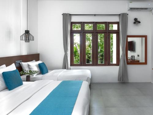 Cette chambre comprend 2 lits et une fenêtre. dans l'établissement Fushi Beach Guesthouse, à Fenfushi