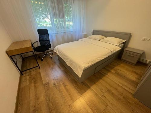 a bedroom with a bed and a desk and a chair at Peony Apartament in Craiova