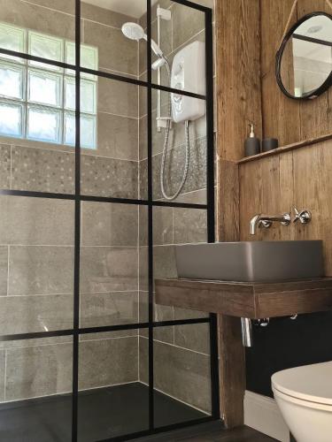 a bathroom with a glass shower with a sink at Rosemary Cottage in Mattishall