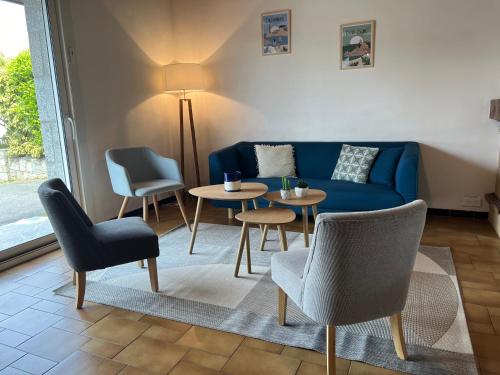 un soggiorno con divano blu, tavoli e sedie di GRANIT COCOON a Saint-Quay-Perros