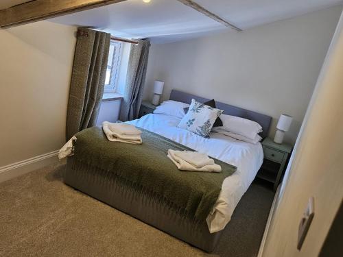 a bedroom with a bed with two towels on it at Rosemary Cottage in Mattishall