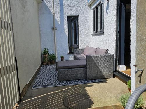 einen Korbstuhl auf der Veranda eines Hauses in der Unterkunft Rosemary Cottage in Mattishall