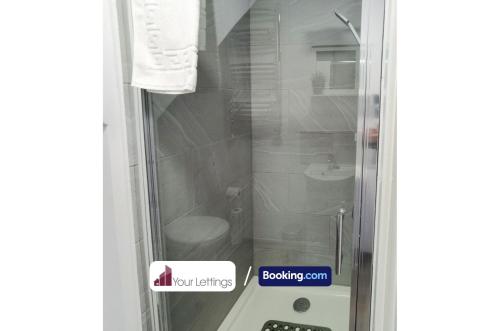 a glass shower door with a toilet in it at 4 Bedroom Contractor House By Your Lettings Short Lets & Serviced Accommodation Peterborough With Free WiFi in Peterborough