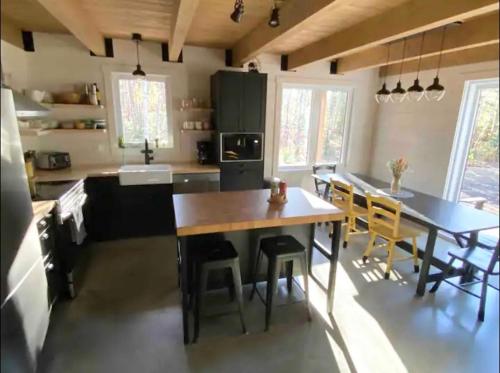 eine Küche mit einem großen Holztisch und Stühlen in der Unterkunft Repaire des bouleaux in Saint-Tite-des-Caps