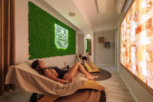 two women laying on beds in a room with a green wall at Marina di Petrolo Hotel & SPA in Castellammare del Golfo
