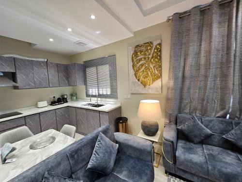 شقة فاخرة Modern Apartment of 3 Bedrooms 5 minutes to Haram في المدينة المنورة: غرفة معيشة مع طاولة وكراسي ومطبخ