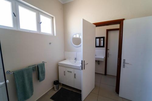 een witte badkamer met een wastafel en een spiegel bij Haus Boost Self Catering in Swakopmund