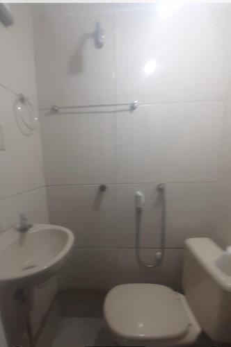 a white bathroom with a toilet and a sink at Suite 2, Casa Amarela, Segundo Andar in Nova Iguaçu