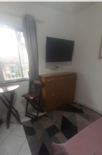 a living room with a television and a desk with a chair at Suite 2, Casa Amarela, Segundo Andar in Nova Iguaçu