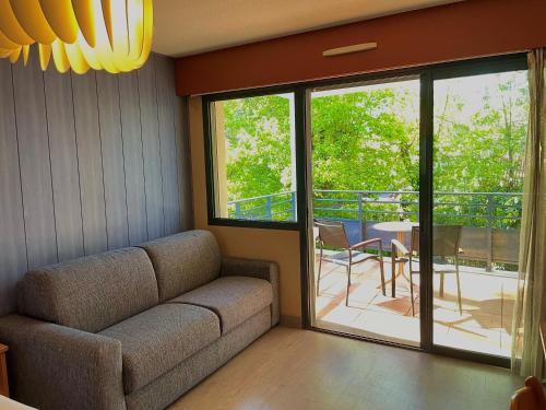 sala de estar con sofá y puerta corredera de cristal en Hotel Le Pavillon Bleu, en Hossegor