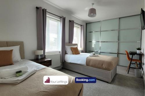 1 dormitorio con 2 camas y mesa con silla en 4 Bedroom House By Your Lettings Short Lets & Serviced Accommodation Peterborough With Free WiFi,Netflix and more en Peterborough