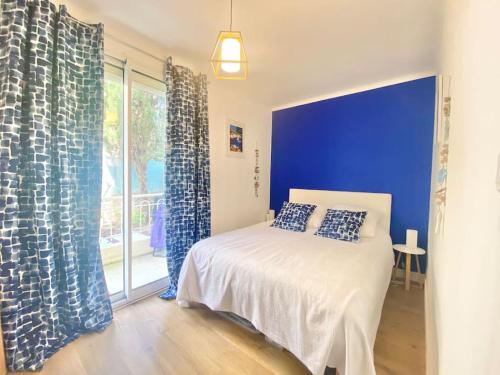 une chambre avec un lit avec un mur bleu dans l'établissement Cannes appartement 1 chambre - Victoriam, à Cannes