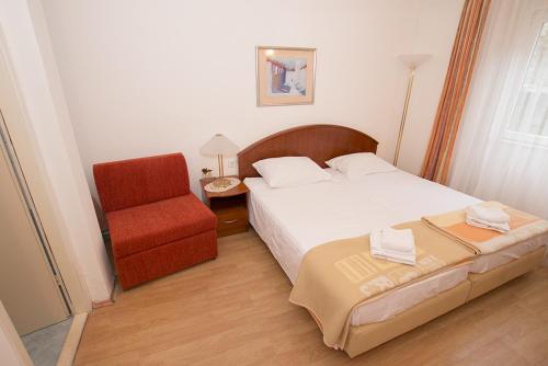 1 dormitorio con 1 cama y 1 silla roja en Guest House Sofija, en Dubrovnik
