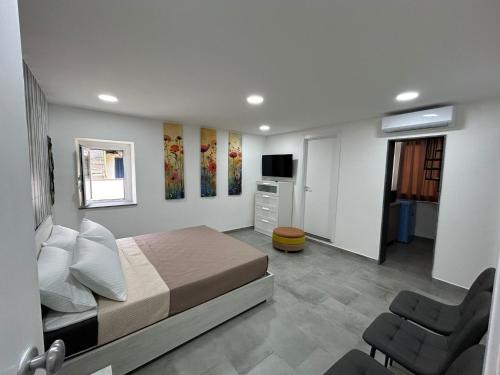 una camera con letto, sedia e televisore di Casa Vacanze Happy Moment a Catania