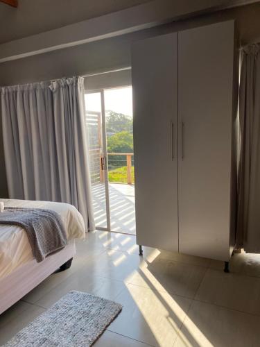 a bedroom with a bed and a large sliding glass door at Onothweni Lodge in Manguzi